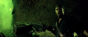 Movie still from “Black Hawk Down” (2001), directed by Ridley Scott – A man holding a machine gun while standing next to a brick wall; Close Up shot, Low angle