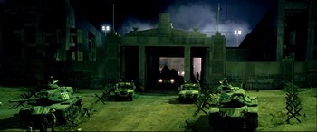 Movie still from “Black Hawk Down” (2001), directed by Ridley Scott – An open garage with a car parked in front of it at night time; Extreme Wide shot, High angle