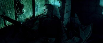 Movie still from “Black Hawk Down” (2001), directed by Ridley Scott – A man sitting in a dark room next to a window; Medium shot, Low angle