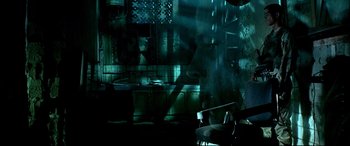 Movie still from “Black Hawk Down” (2001), directed by Ridley Scott – A dark room with a chair in the foreground and cabinets in the background; Wide shot, Over the shoulder angle