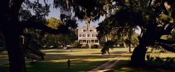 Movie still from “Dear John” (2010), directed by Lasse Hallström – A person walking on a lush green field near a large house; Extreme Wide shot, High angle