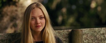 Movie still from “Dear John” (2010), directed by Lasse Hallström – A beautiful young lady sitting on top of a wooden bench; Close Up shot, Over the shoulder angle