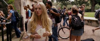 Movie still from “Dear John” (2010), directed by Lasse Hallström – A woman standing on a brick sidewalk holding a pair of tickets; Medium shot, Over the shoulder angle