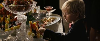 Movie still from “Dear John” (2010), directed by Lasse Hallström – A young boy sitting at a table with a plate of fruit; Medium shot, Over the shoulder angle