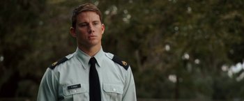Movie still from “Dear John” (2010), directed by Lasse Hallström – A man in a uniform is standing in front of trees; Close Up shot, Over the shoulder angle