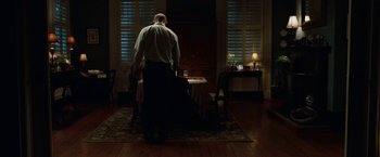 Movie still from “Dear John” (2010), directed by Lasse Hallström – A man standing at a table in front of a window; Wide shot, Low angle