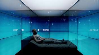 Movie still from “Black Mirror” (2011), created by Charlie Brooker – A man laying on top of a bed inside of a room; Wide shot, Overhead angle