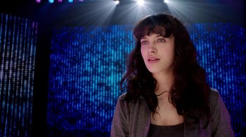 Movie still from “Black Mirror” (2011), created by Charlie Brooker – A beautiful young woman standing in front of a stage; Close Up shot, Low angle