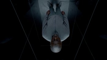 Movie still from “Black Mirror” (2011), created by Charlie Brooker – A man standing in the middle of a room; Medium shot, Overhead angle