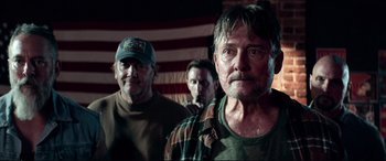 Movie still from “Debt Collectors” (2020), directed by Jesse V. Johnson – A group of men standing next to each other in front of an american flag; Close Up shot, Over the shoulder angle
