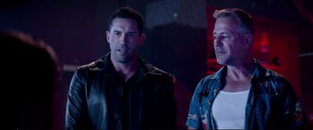 Movie still from “Debt Collectors” (2020), directed by Jesse V. Johnson – Two men standing next to each other in a dark room; Medium shot, Low angle