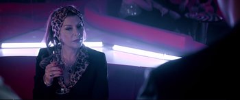 Movie still from “Debt Collectors” (2020), directed by Jesse V. Johnson – A woman in a black jacket and a leopard print scarf; Close Up shot, Over the shoulder angle