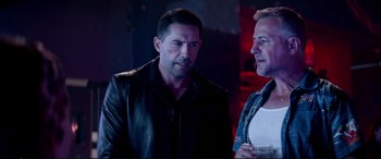 Movie still from “Debt Collectors” (2020), directed by Jesse V. Johnson – Two men are talking in a dark room; Medium shot, Over the shoulder angle