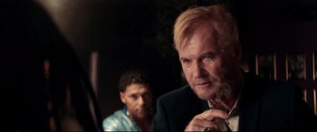 Movie still from “Debt Collectors” (2020), directed by Jesse V. Johnson – A man smoking a cigarette in front of another man in a suit; Close Up shot, Over the shoulder angle
