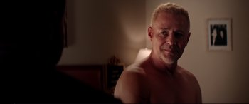Movie still from “Debt Collectors” (2020), directed by Jesse V. Johnson – A man with blonde hair and a bare chest; Close Up shot, Over the shoulder angle
