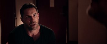 Movie still from “Debt Collectors” (2020), directed by Jesse V. Johnson – A person sitting in front of a door; Close Up shot, Over the shoulder angle