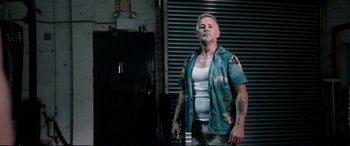 Movie still from “Debt Collectors” (2020), directed by Jesse V. Johnson – A man standing in front of a door wearing a blue shirt; Medium shot, Low angle