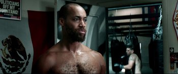 Movie still from “Debt Collectors” (2020), directed by Jesse V. Johnson – A man with a beard in the gym; Close Up shot, Low angle