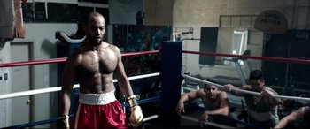 Movie still from “Debt Collectors” (2020), directed by Jesse V. Johnson – Two men in a boxing ring with one man laying on the ground; Medium shot, Low angle