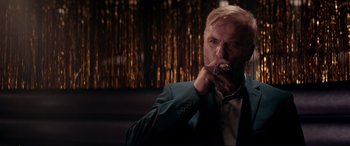 Movie still from “Debt Collectors” (2020), directed by Jesse V. Johnson – A man in a suit smoking a cigarette in front of a wall; Close Up shot, Low angle