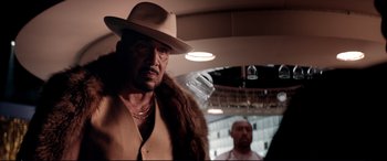 Movie still from “Debt Collectors” (2020), directed by Jesse V. Johnson – A man in a hat and a fur coat standing next to another man in a car; Close Up shot, Over the shoulder angle