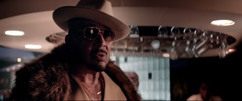 Movie still from “Debt Collectors” (2020), directed by Jesse V. Johnson – A person wearing a hat and sunglasses; Close Up shot, Over the shoulder angle