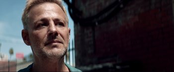 Movie still from “Debt Collectors” (2020), directed by Jesse V. Johnson – A person wearing a green shirt; Close Up shot, Low angle