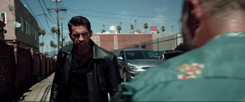 Movie still from “Debt Collectors” (2020), directed by Jesse V. Johnson – A man in a leather jacket is walking down the street; Medium shot, Over the shoulder angle