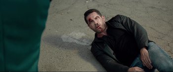 Movie still from “Debt Collectors” (2020), directed by Jesse V. Johnson – A man laying on the ground covered in blood; Medium shot, High angle