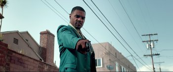 Movie still from “Debt Collectors” (2020), directed by Jesse V. Johnson – A man in a green suit is holding a gun; Medium shot, Low angle