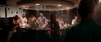 Movie still from “Debt Collectors” (2020), directed by Jesse V. Johnson – A group of people standing around in a bar; Medium shot, Over the shoulder angle