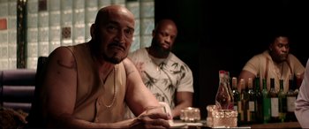 Movie still from “Debt Collectors” (2020), directed by Jesse V. Johnson – A man sitting at a table with a glass of wine; Medium shot, Over the shoulder angle