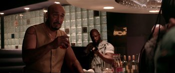 Movie still from “Debt Collectors” (2020), directed by Jesse V. Johnson – Two men are standing at a bar and one of them is holding a drink; Medium shot, Over the shoulder angle