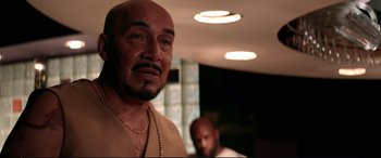 Movie still from “Debt Collectors” (2020), directed by Jesse V. Johnson – A man with a beard and a necklace is looking at the camera; Close Up shot, Low angle