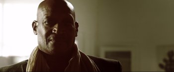 Movie still from “Debt Collectors” (2020), directed by Jesse V. Johnson – A man with a shaved bald head is smiling for the camera; Close Up shot, Low angle