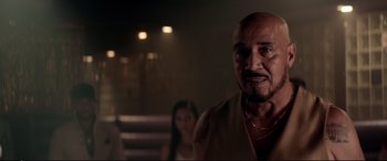 Movie still from “Debt Collectors” (2020), directed by Jesse V. Johnson – An older man is looking at the camera while a young woman looks on; Close Up shot, Over the shoulder angle