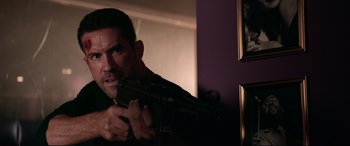 Movie still from “Debt Collectors” (2020), directed by Jesse V. Johnson – A man holding a gun in a room; Close Up shot, Over the shoulder angle