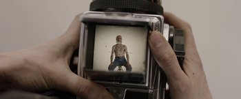 Movie still from “Disobedience” (2017), directed by Sebastián Lelio – An old man is taking a picture of himself with an old camera; Extreme Close Up shot, Overhead angle