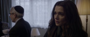 Movie still from “Disobedience” (2017), directed by Sebastián Lelio – A person sitting in a room near a window; Close Up shot, Over the shoulder angle