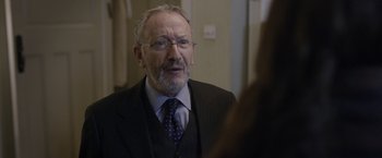 Movie still from “Disobedience” (2017), directed by Sebastián Lelio – An older man wearing a suit and tie; Close Up shot, Over the shoulder angle
