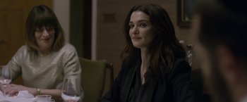 Movie still from “Disobedience” (2017), directed by Sebastián Lelio – A woman sitting at a table in front of other people; Close Up shot, Over the shoulder angle