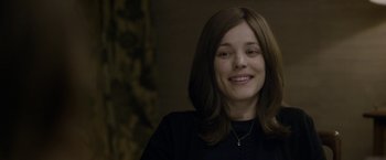 Movie still from “Disobedience” (2017), directed by Sebastián Lelio – A young woman smiling for the camera in front of a wall; Close Up shot, Over the shoulder angle