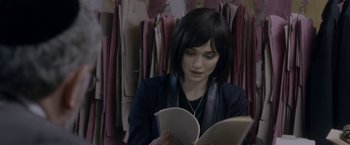 Movie still from “Disobedience” (2017), directed by Sebastián Lelio – A woman is reading a book in a store; Medium shot, Over the shoulder angle