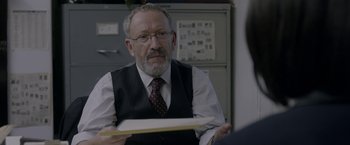 Movie still from “Disobedience” (2017), directed by Sebastián Lelio – An older man wearing a vest and a tie; Close Up shot, Over the shoulder angle