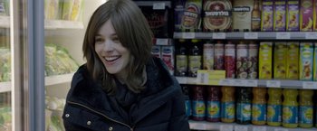 Movie still from “Disobedience” (2017), directed by Sebastián Lelio – A woman smiling in front of a shelf full of drinks; Close Up shot, Over the shoulder angle