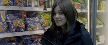 Movie still from “Disobedience” (2017), directed by Sebastián Lelio – A woman in a black jacket in front of a shelf of food; Close Up shot, Over the shoulder angle