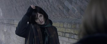 Movie still from “Disobedience” (2017), directed by Sebastián Lelio – A woman in a scarf standing in front of a brick wall; Close Up shot, Over the shoulder angle
