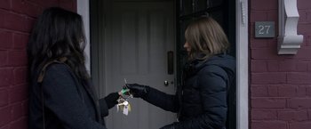 Movie still from “Disobedience” (2017), directed by Sebastián Lelio – A woman is handing keys to another person; Medium shot, High angle