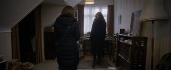 Movie still from “Disobedience” (2017), directed by Sebastián Lelio – Two women standing in front of a window in a cluttered room; Wide shot, Over the shoulder angle