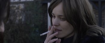 Movie still from “Disobedience” (2017), directed by Sebastián Lelio – A young woman smoking a cigarette in a black shirt; Close Up shot, Over the shoulder angle